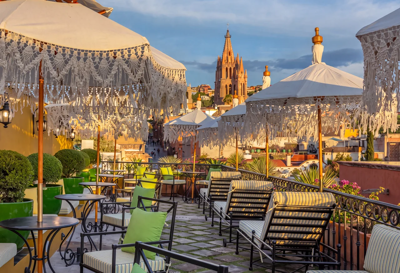 Terraza de Casa Julieta con sombrillas de flecos y la Parroquia de San Miguel Arcángel al fondo